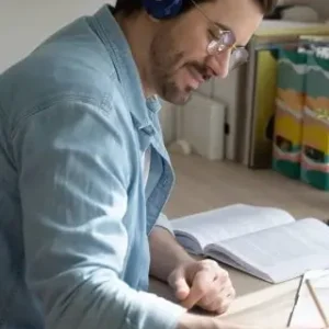 ein Mann trägt Kopfhörer und schreibt etwas in ein Notizbuch