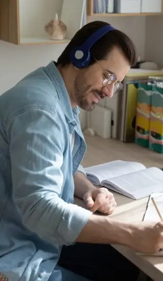 ein Mann trägt Kopfhörer und schreibt etwas in ein Notizbuch